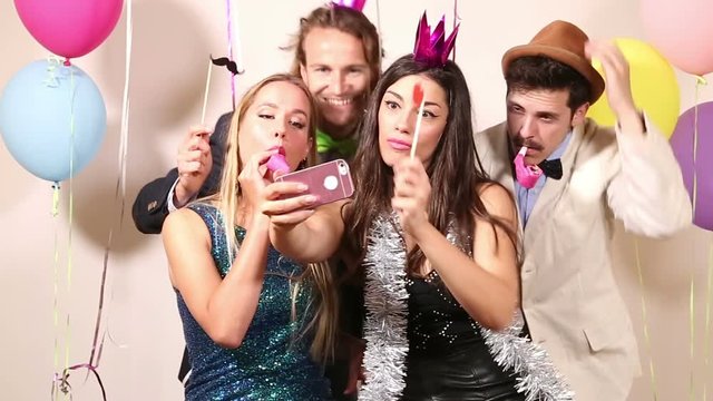 Group of beautiful happy friends taking selfie in photo booth 