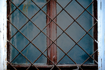 Old window with an rusty grating on a old wall with bricks