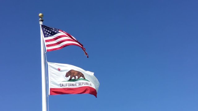 4K HD Video of American flag and California flag waving in the wind, blue sky background