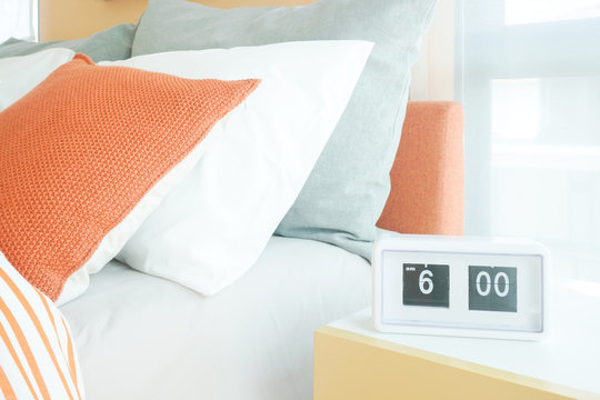 White modern alarm clock on night table next to bed