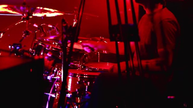 Drummer on stage. Drummer playing on drum set at a rock concert. Contrasting red and blue lights and spotlights.