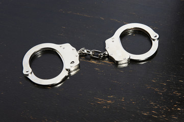 Handcuffs isolated on black wooden table