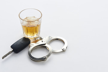 Handcuffs, keys and glass of alcohol on ice with copy space