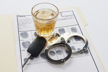 Handcuffs with fingerprints keys and glass of alcohol on ice