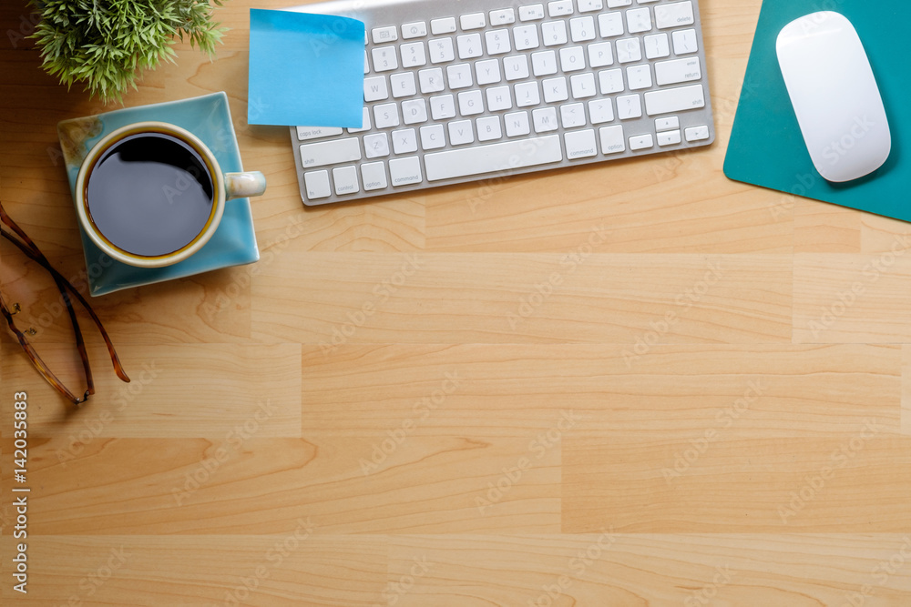 Poster view from above with copy space of notepad, computer and coffee cup on wood work table.