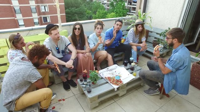High angle view of young friends eating pizza on the rooftop terrace