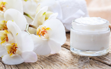 Fototapeta na wymiar Moisturizing cream and orchid on wooden background