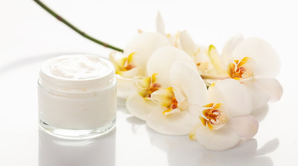 Moisturizing cream and orchid on white background