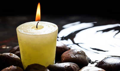 Candle and pebbles in water background