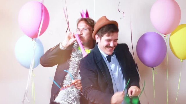 Two funny male friends having fun with props in photo booth, graded
