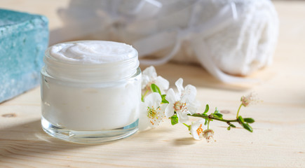 Moisturizing cream and almond blooms on wooden background