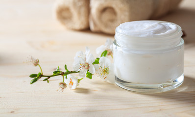 Moisturizing cream and almond blooms on wooden background