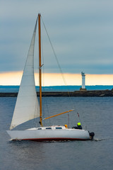 Fototapeta premium White sailboat traveling past the lighthouse in Riga