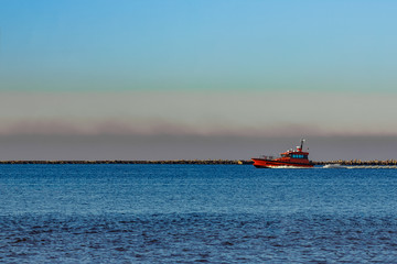 Red pilot ship moving past the breakwater dam in Riga, Europe