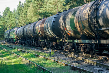 Freight train with tank wagons moving in forest. Green diesel ca