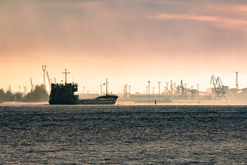 Cargo ship silhouette entering a port of Riga at the morning