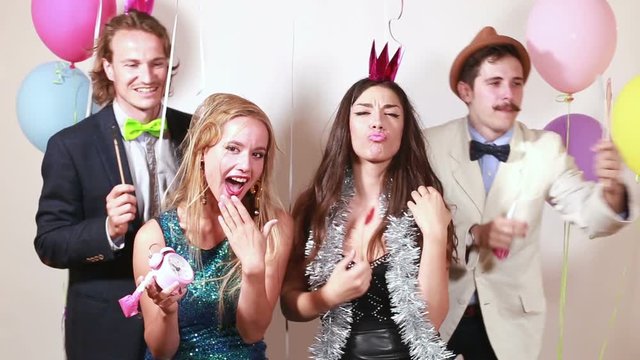 Beautiful young friends having fun in party photo booth