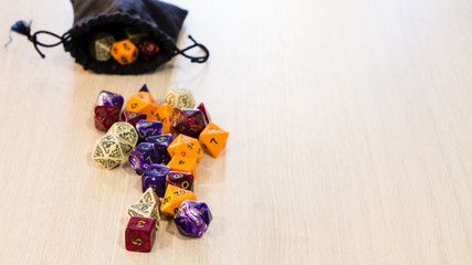 Obraz na płótnie Canvas Colorful roleplaying dice scattered on a table with a linen dice pouch