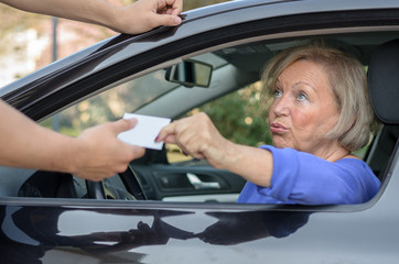 Concerned elderly driver handing over her licence