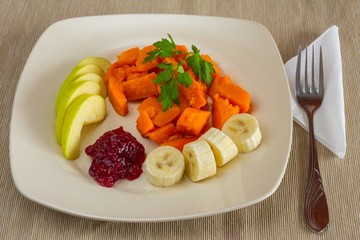 Breakfast plate square rounded corners beige filled dessert salad of roasted pumpkin slices of banana and green Apple with the addition of cherry jam and decoration of sprigs of parsley 