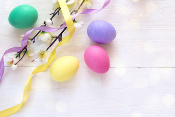 Easter eggs and apple tree branch on white wooden background.