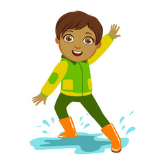 Boy In Green And Yellow Jacket, Kid In Autumn Clothes In Fall Season Enjoyingn Rain And Rainy Weather, Splashes And Puddles