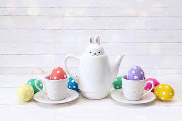 Kettle-hare with cups and Easter eggs on a white background.