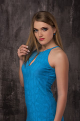 Beautiful happy young woman in blue dress on grey background