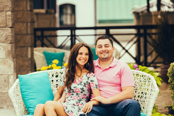 Funny couple laughing sitting on bench outdoors