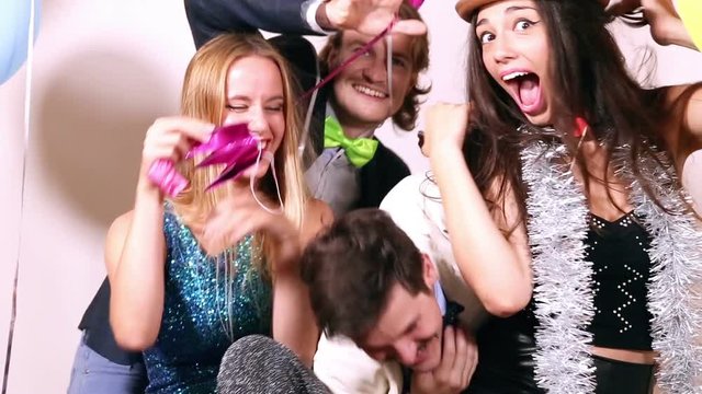 Two young cute couples having fun in party photo booth, graded