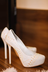 Obraz premium white wedding shoes with shiny rhinestones on a brown wooden background
