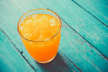top view orange juice in glass with ice on ocean blue wooden summer time concept.