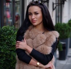 Portrait of a girl in a fur vest on the street