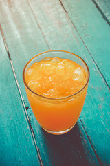 top view orange juice in glass with ice on ocean blue wooden summer time concept.