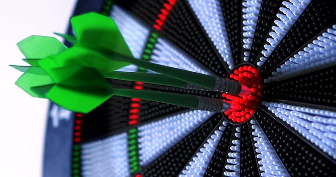 Video footage of three green darts hitting the bullseye on a dartboard. 4K video footage