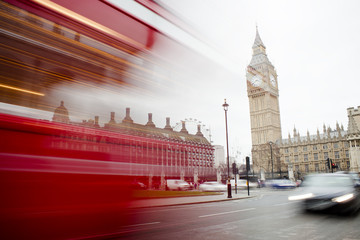 Red London bus passing in Central city with Big Ben in background