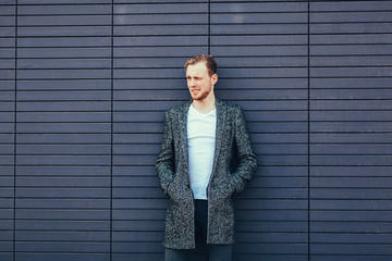 handsome man in coat smiling on blue background. copy space