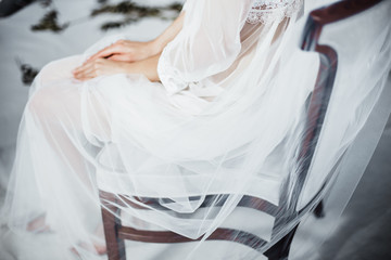 beautiful girl in white transparent boudoir gown of tulle and lace sitting on a chair hands close-up