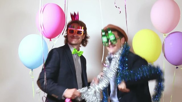 Two funny friends dancing and laughing in party photo booth