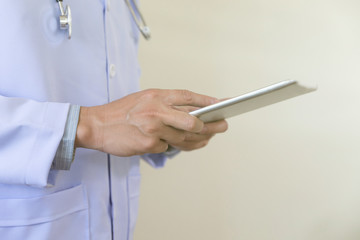 doctor in white lab coat using his tablet computer at work