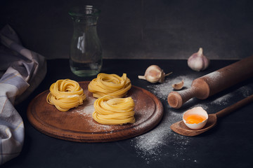 Raw homemade pasta with flour and spices on the rustic background.
