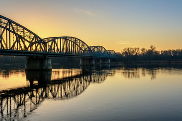 Jozef Pilsudski road bridge reflected in Vistula river in the morning. Torun, Poland. Europe.
