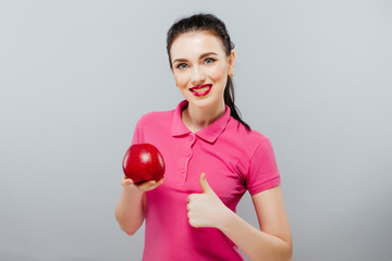 Young beautiful sexy girl with dark curly hair, bare shoulders and neck, holding big red apple to enjoy the taste and are dieting, healthy eating and organic foods, feeling temptation, smile, teeth.