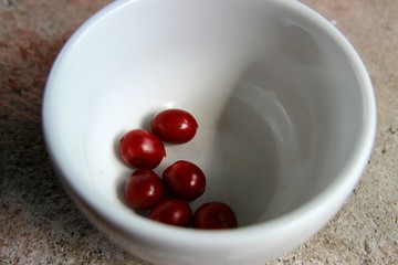 Closeup of raw coffee cherries in a small white cup