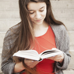 Young beautiful woman enjoying reading interesting books in old center of europe city (Knowledge, development, education, success concept)