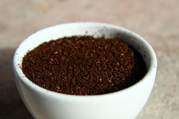 Closeup of grinded coffee beans in a small white cup
