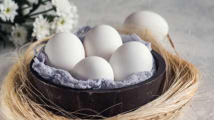 White eggs in wooden bowl on white background, selective focuse