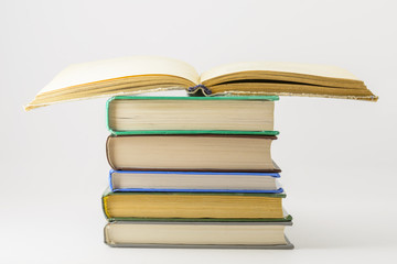 Many closed books lying on a white background.One open book.