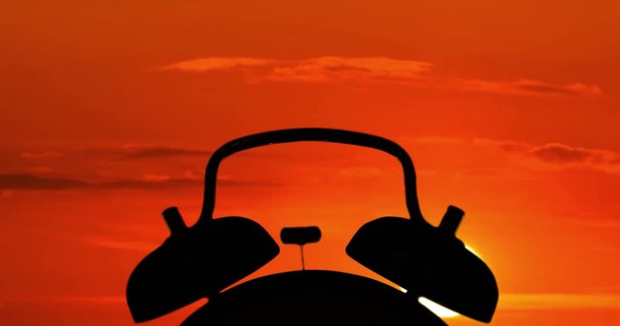 Time lapse of silhouette of alarm clock ringing at sunrise time in the morning. Professional shot in 4K resolution.