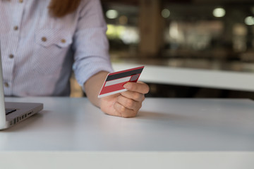 woman holding credit card with laptop computer for online shopping